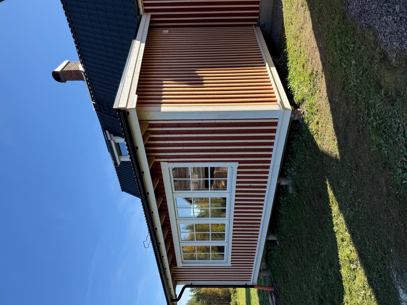 Tillbyggt uterum med röd panel och spröjsade fönster